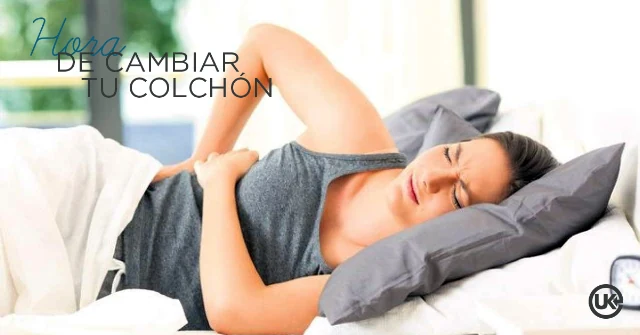 Mujer acostada en la cama con gesto de dolor de espalda, señal de que es hora de cambiar el colchón